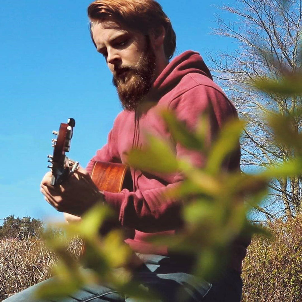 Den norske skuespilleren Vegard Heggelund spiller gitar i nydelig natur.